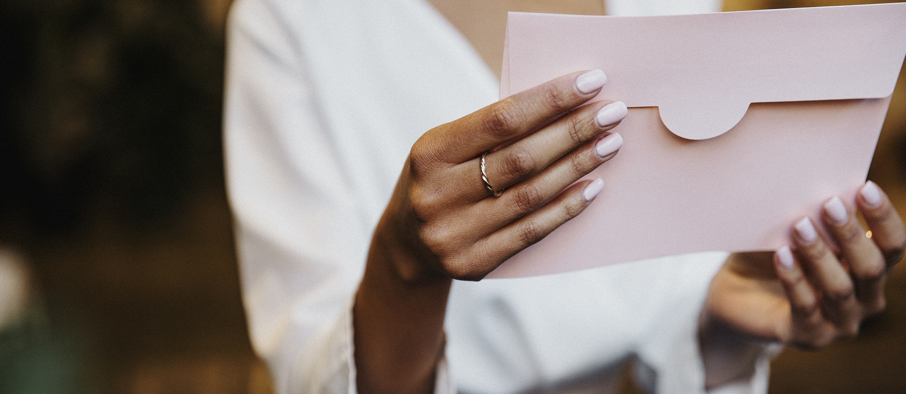 Option envoyé pour vous Une personne tient une enveloppe rose poudrée entre ses mains